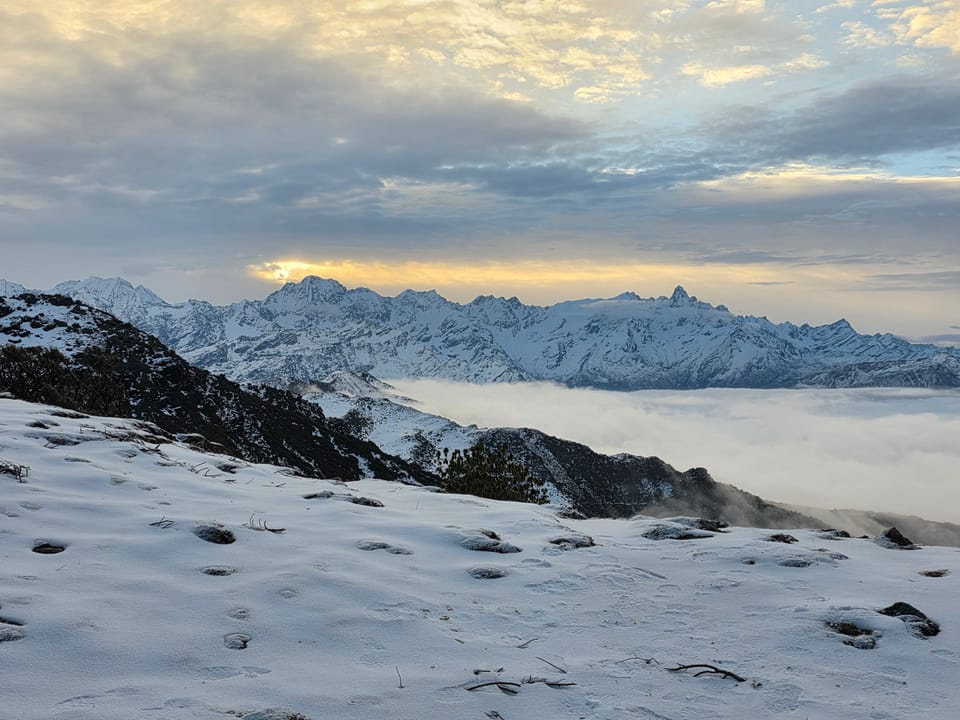Jagged snow peaks lit by a low sun above a cloud inversion