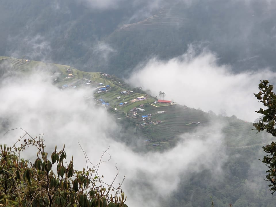 A terraced Himalayan hillside village seen through drifting cloud