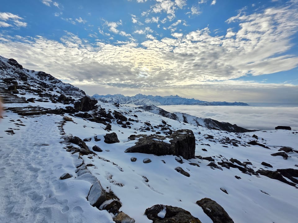 Sunlight breaking through clouds over a snowy mountain ridge