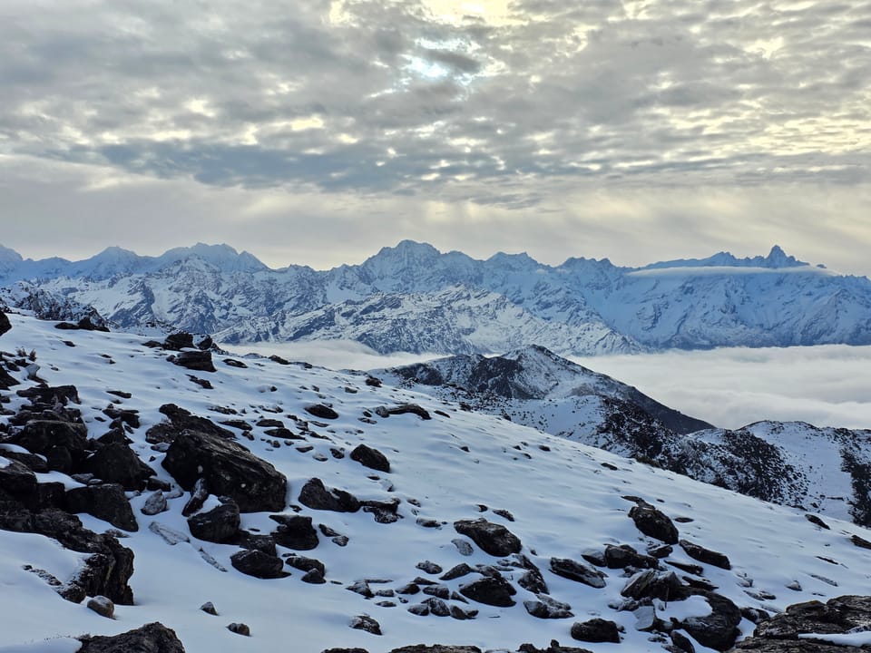 A snow-covered ridge overlooking a sea of clouds at dusk